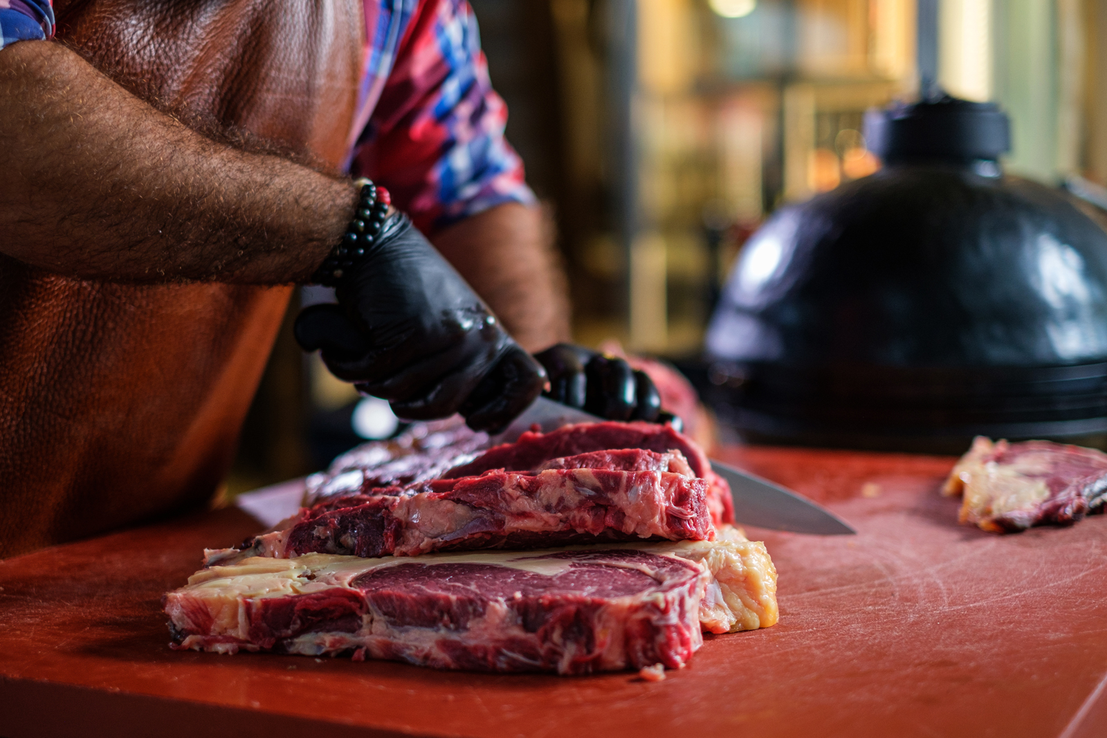 Schneidebrett mit Fleisch vor Keramikgrill